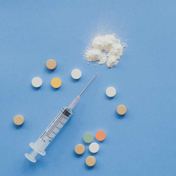 Photo depicting a syringe, white powder, and pill