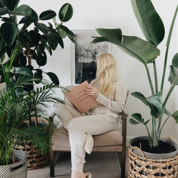a woman sits between two plants reading a book