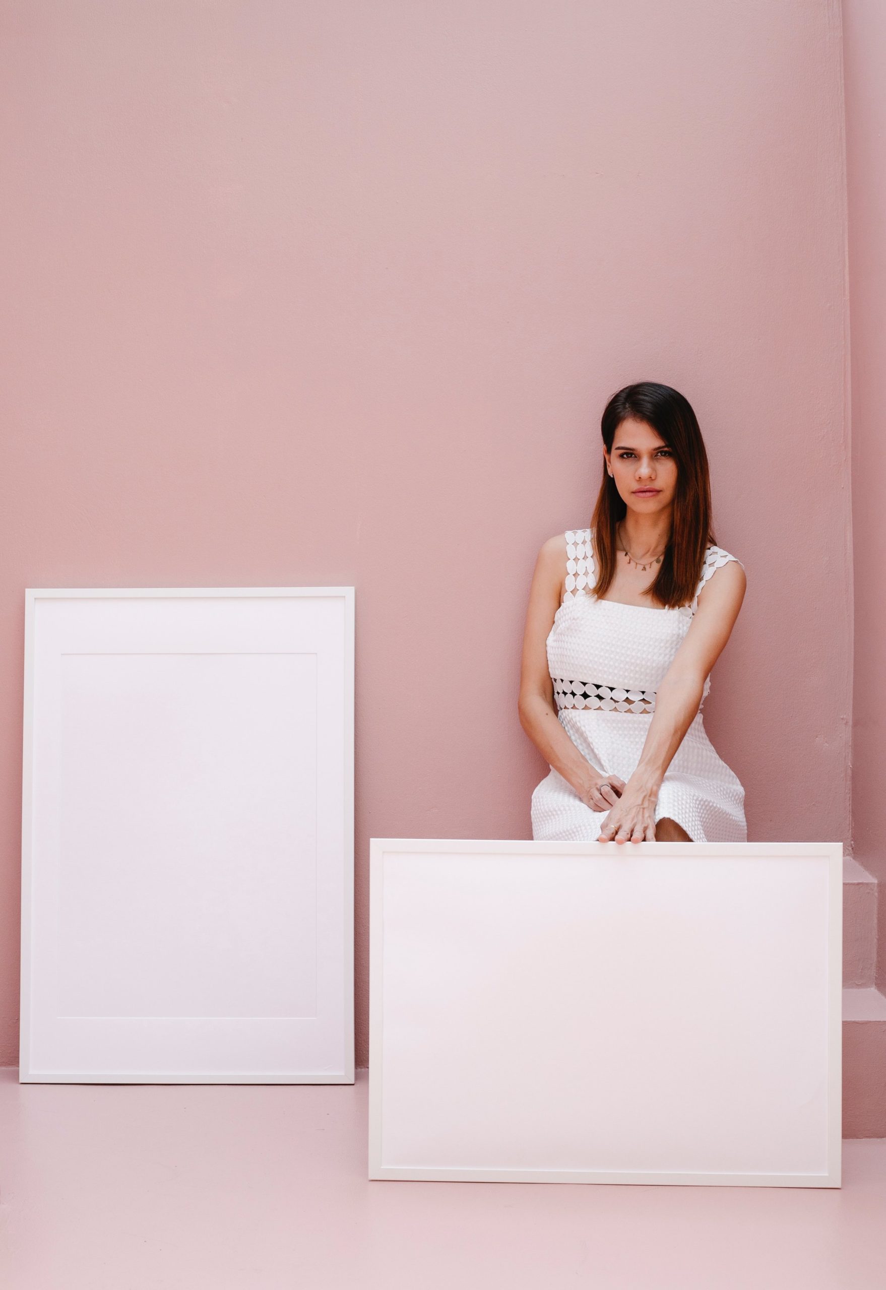 a woman sits with two white blank picture frames
