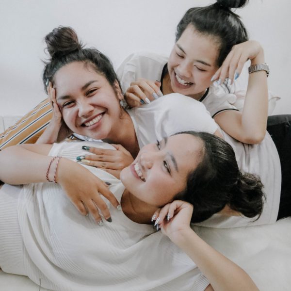 three young women laying down and smiling