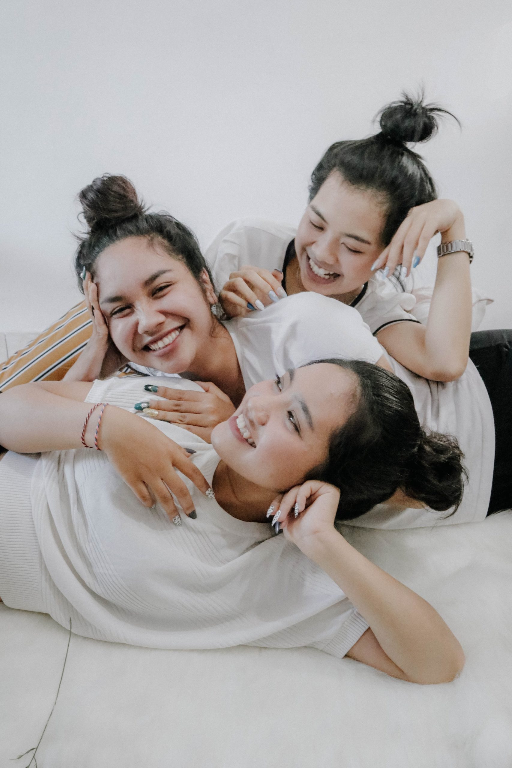 three young women laying down and smiling