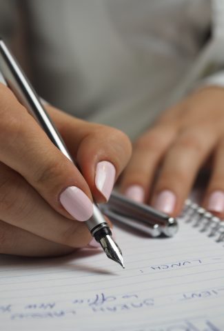 Hands of a woman writing in a notebook