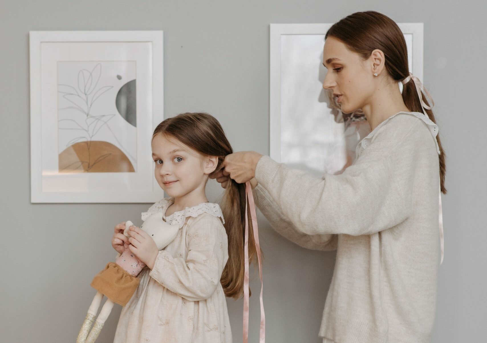 A mother tying her daughter's hair with a ribbon