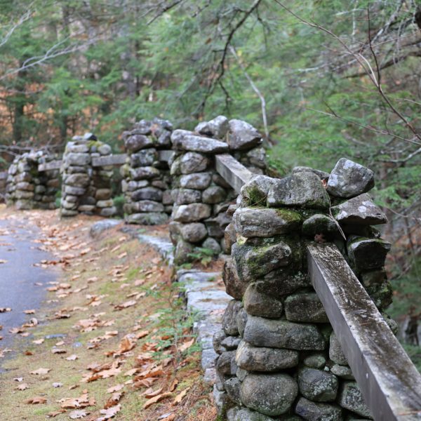 a stone wall that begins in the foreground and fades into the background along the bend of a country road