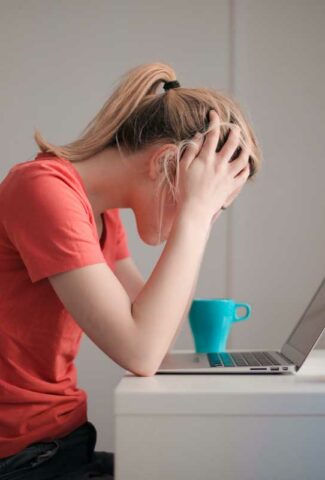 Woman frustrated with head down at computer.