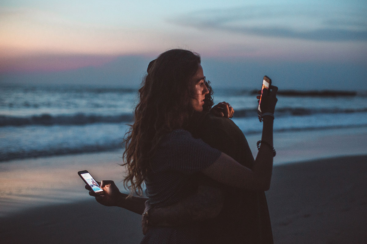 Couple hugging while looking at their phones